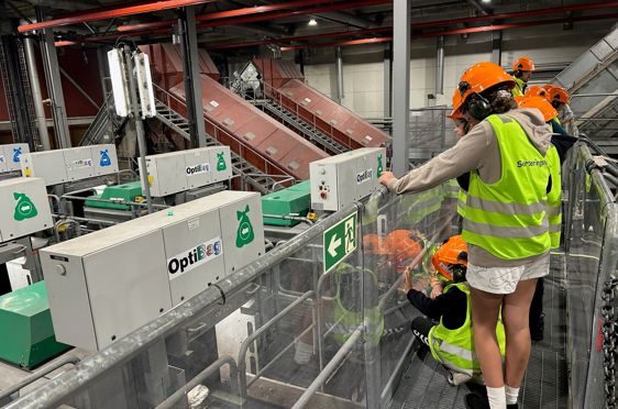 en gruppe mennesker iført sikkerhetsvester som jobber på en maskin